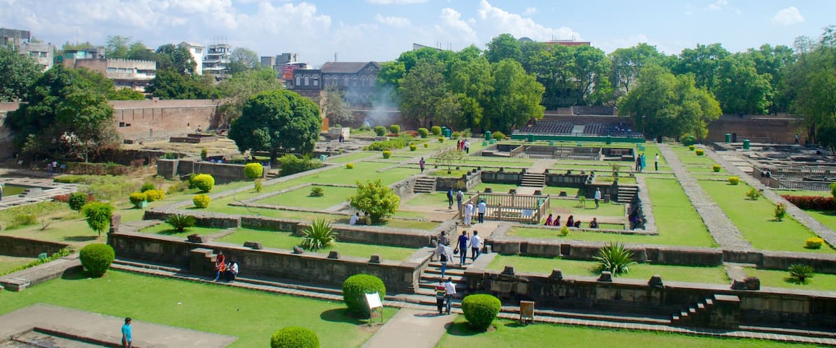 A historical site with ruins, green lawns, and trees.