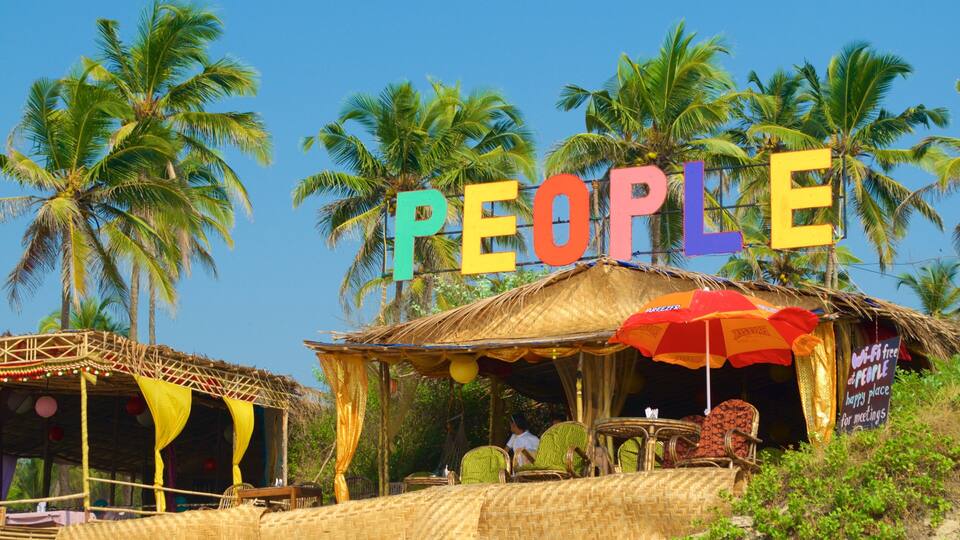 A beachside hut with colorful letters spelling "PEOPLE" above it, surrounded by palm trees.