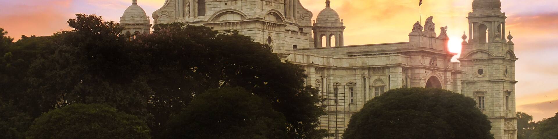 A large domed building with multiple smaller domes and statues, set against a sunset sky.