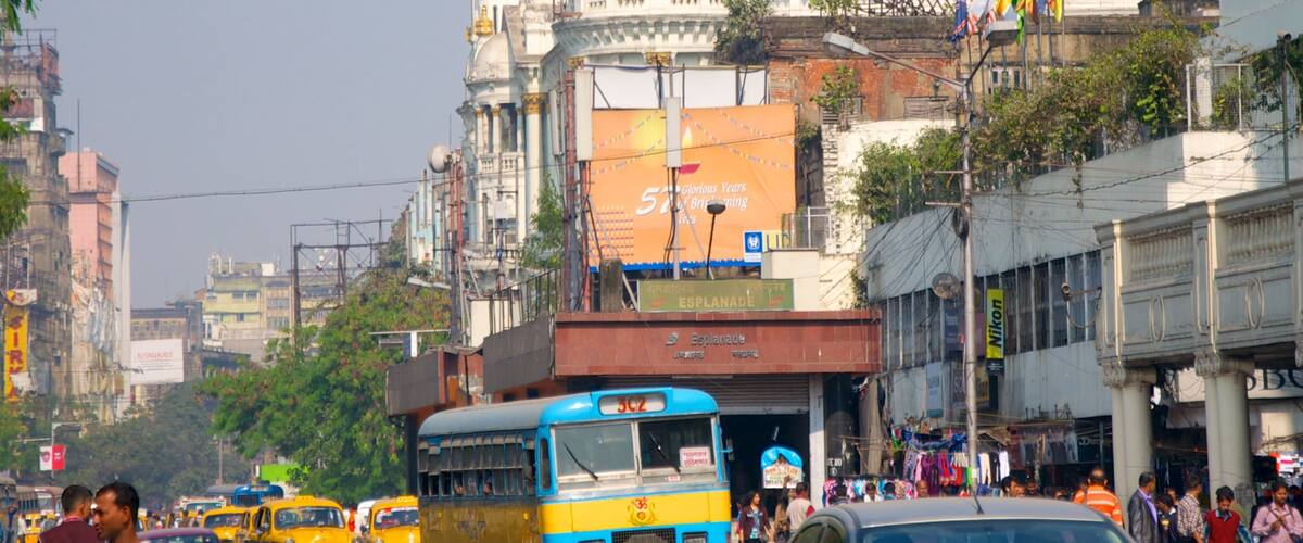 A busy urban street with a blue and yellow bus, cars, and pedestrians.