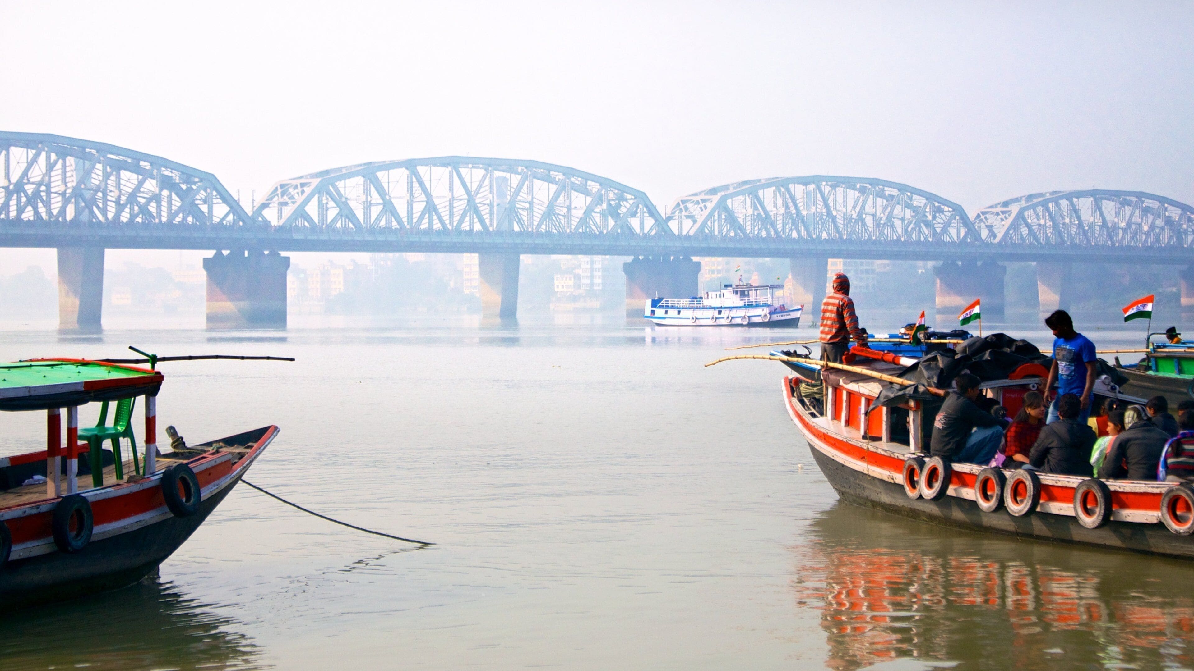 A river with boats, a bridge, and foggy weather.