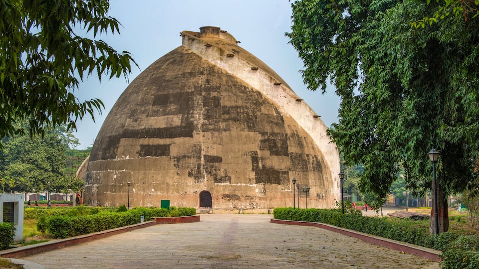 A large, dome-shaped building with a central entrance, surrounded by well-maintained greenery and a paved walkway.