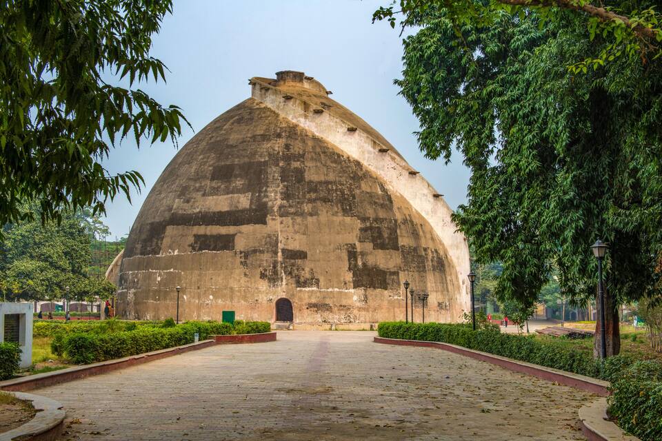 A large, dome-shaped building with a central entrance, surrounded by well-maintained greenery and a paved walkway.