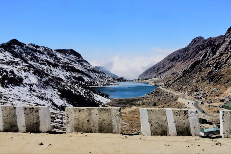 A mountainous landscape with a lake, a road, and scattered buildings.