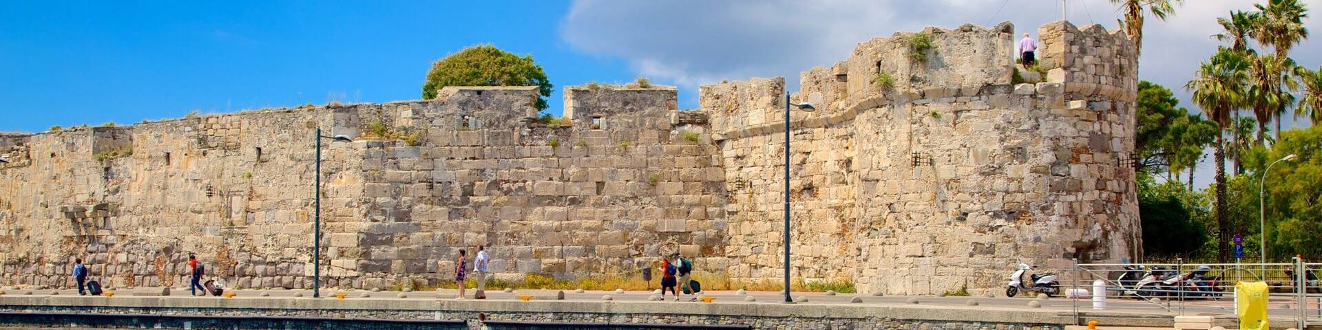 A historic stone wall with a clear blue sky and a flag.