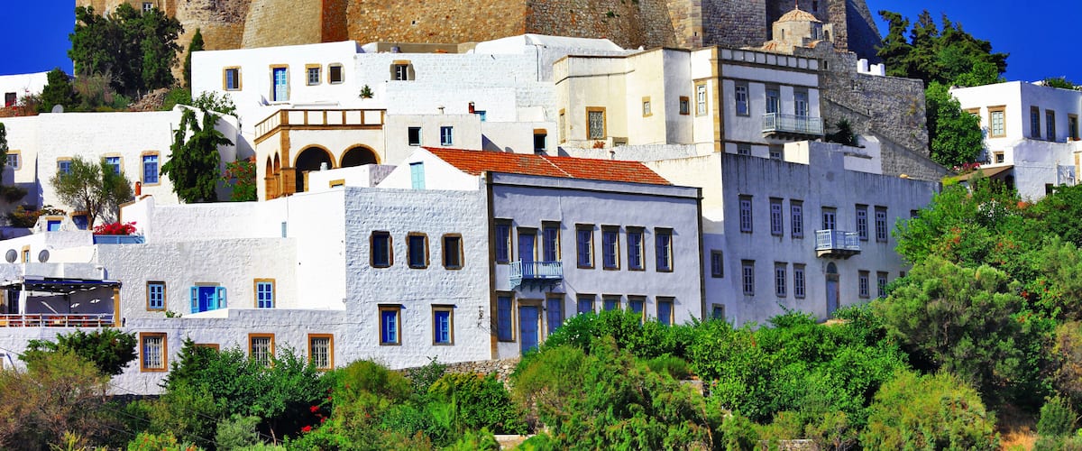 A historic castle atop a hill with white buildings in the foreground.