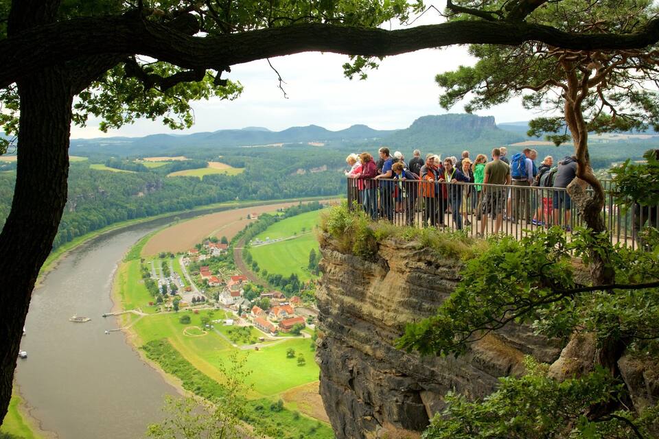 Eine Gruppe von Menschen auf einer Klippe mit Blick auf einen Fluss und eine Stadt.