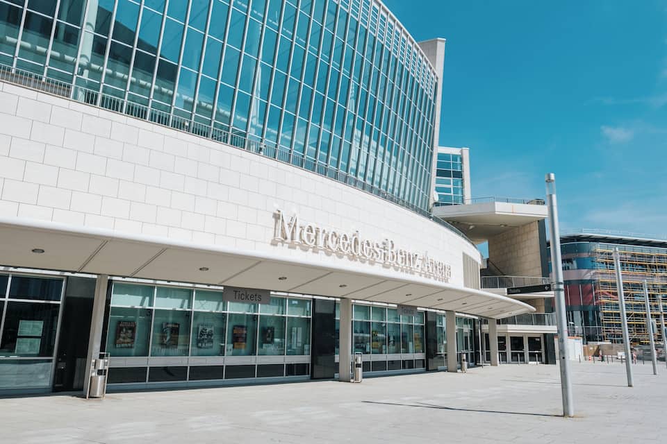A modern building with large glass windows and a sign reading "Mercedes-Benz Museum".