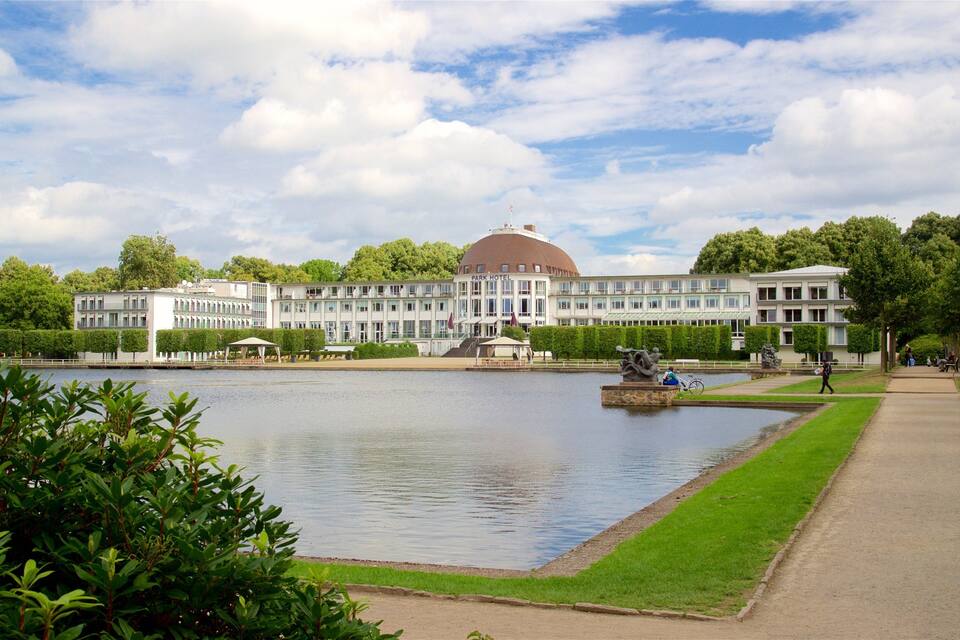 Een groot hotel met een koepel, een meer en een park met een wandelpad.