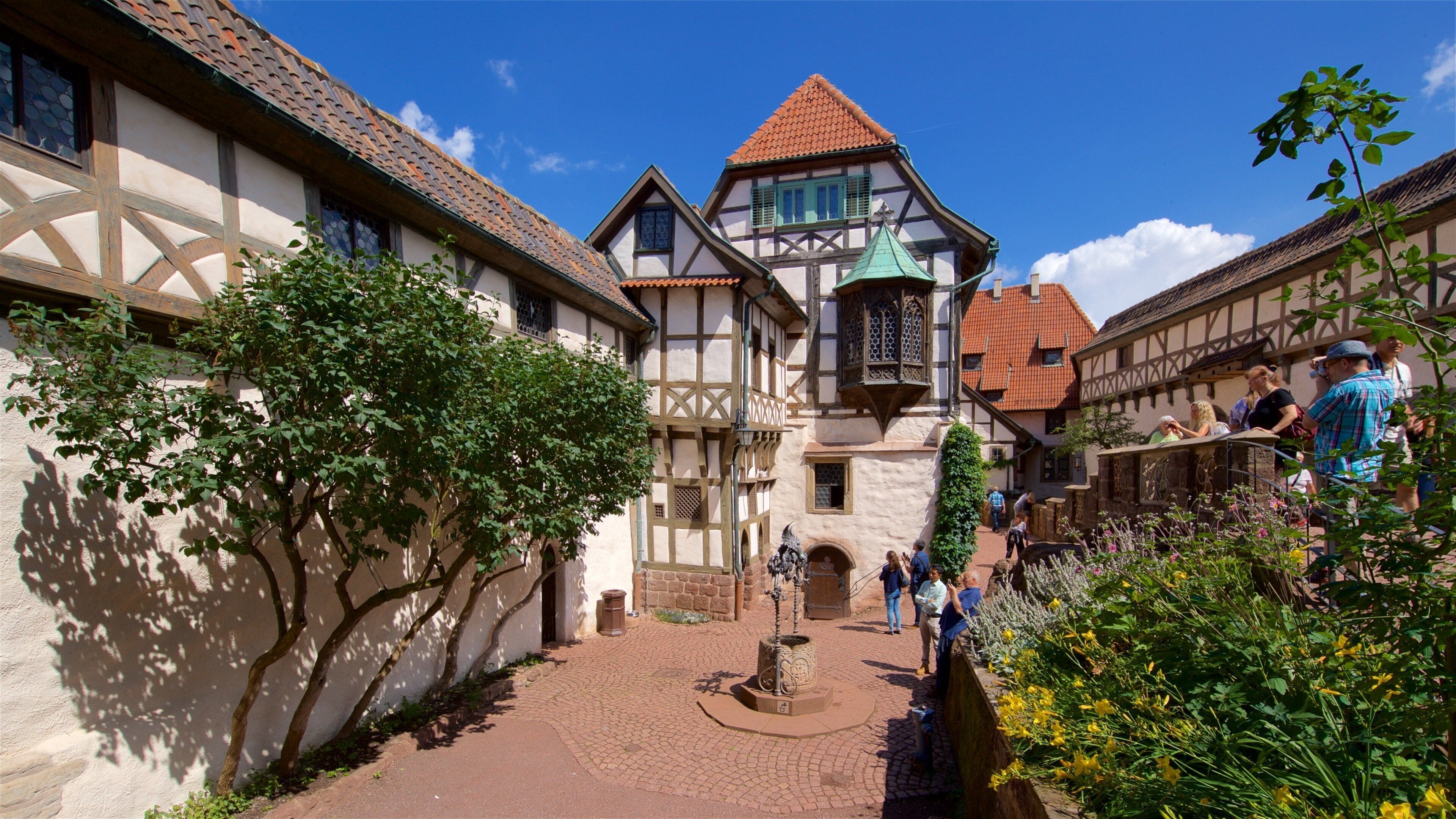 A medieval European village with timber-framed houses, cobblestone streets, and a central fountain.