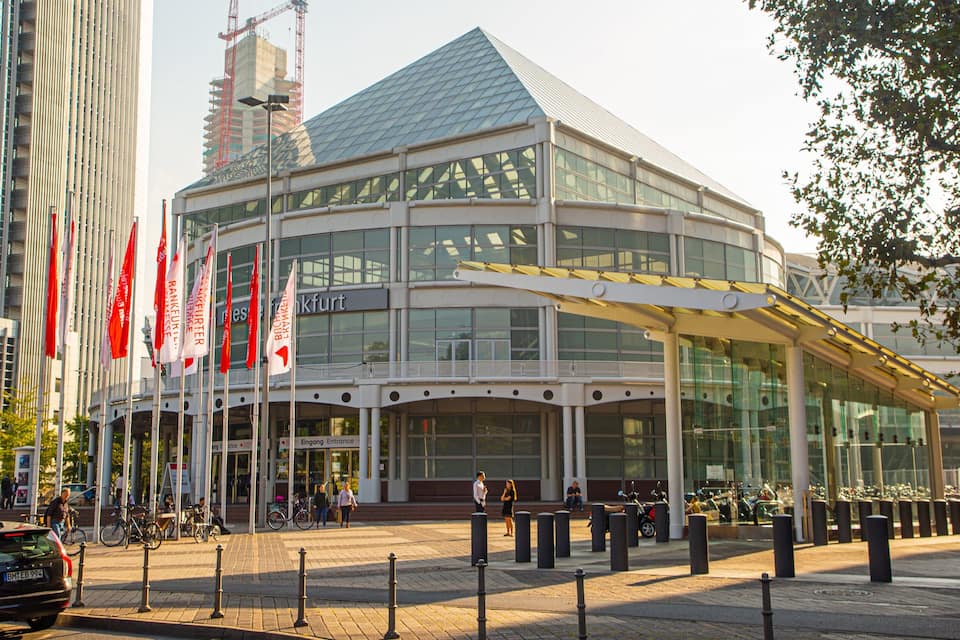 A modern building with a glass facade and a distinctive roof.