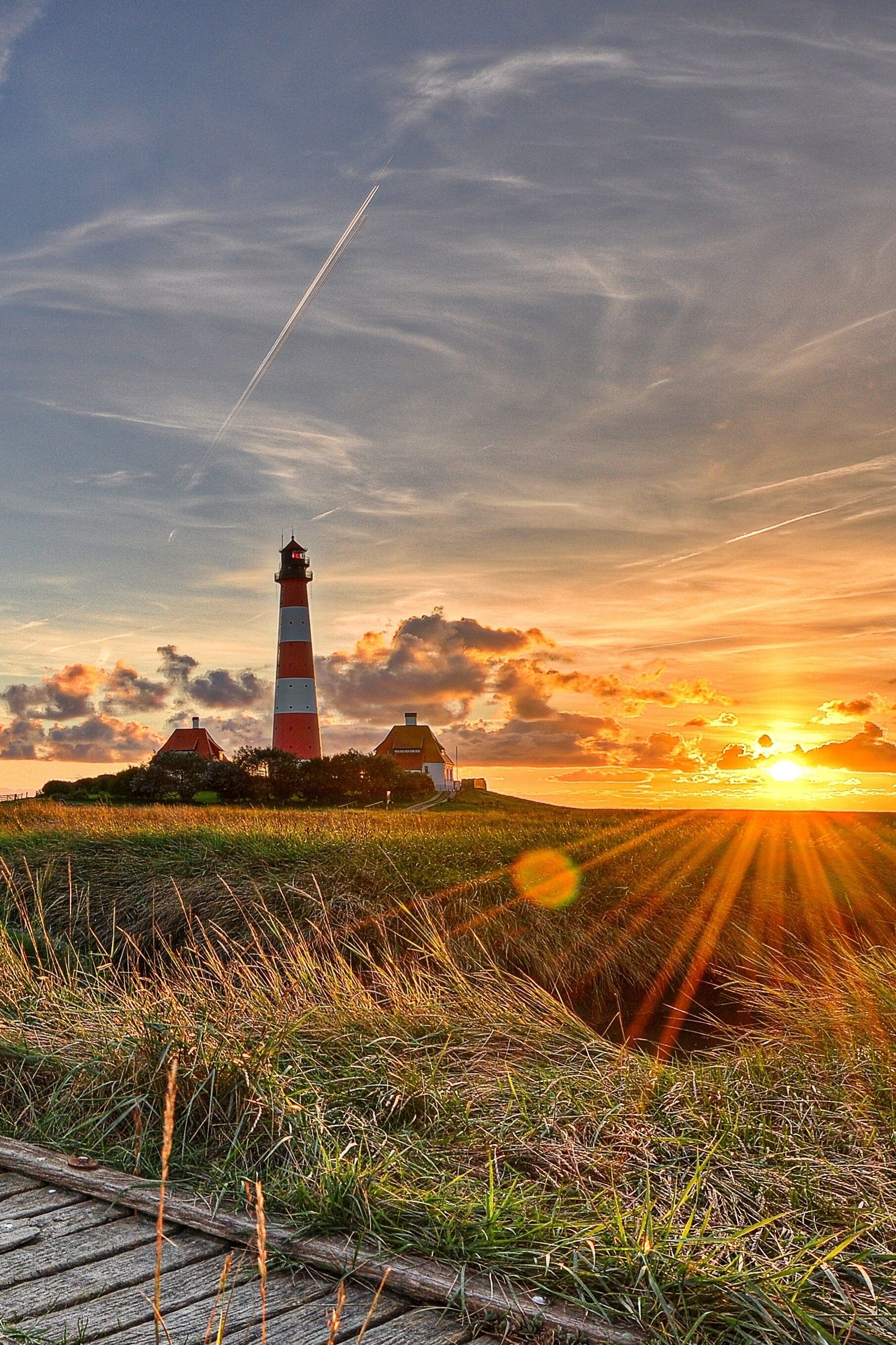 A lighthouse, grassy field, and sunset.