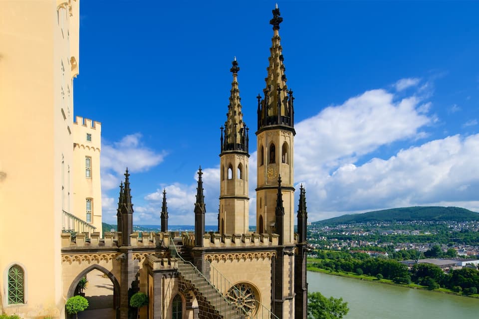 Una catedral histórica con dos torres gemelas y un alto campanario, con vistas a un río y una ciudad.