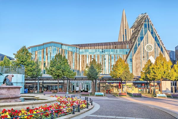 A modern building with a glass facade and a unique triangular tower.