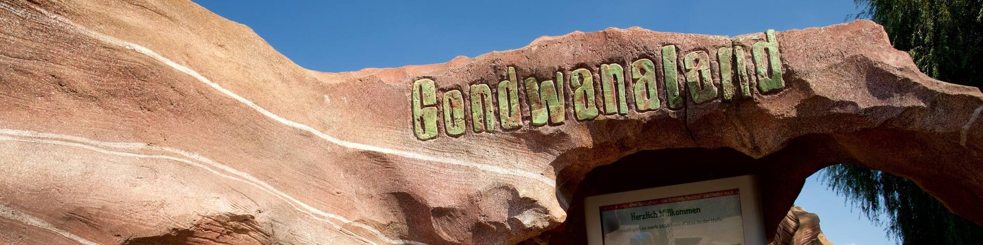 A rock formation with the text 'Gondwana Land' and a sign with German text.