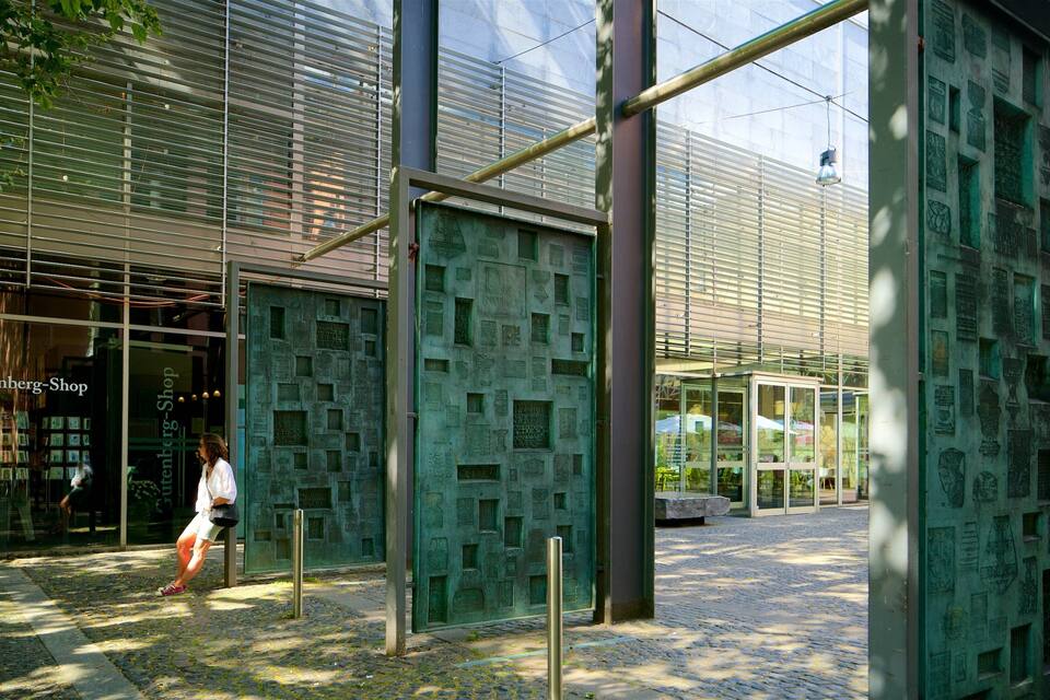 A modern building with a glass facade and a bronze plaque wall.