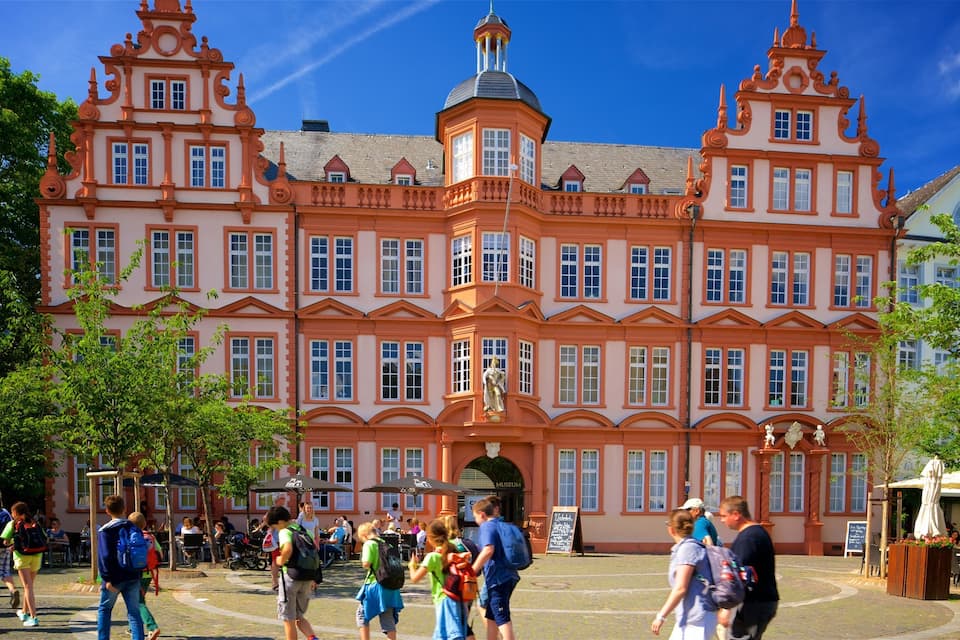 A large, ornate building with multiple windows and statues in front.