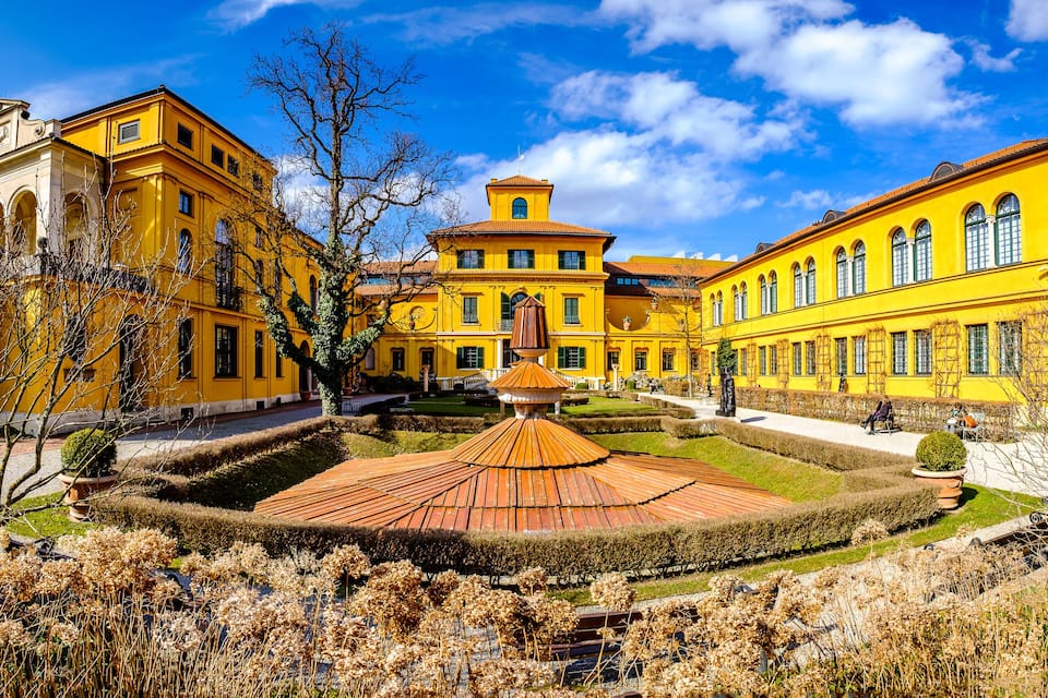 Un ensemble de bâtiments jaunes avec un jardin central et un petit pavillon.