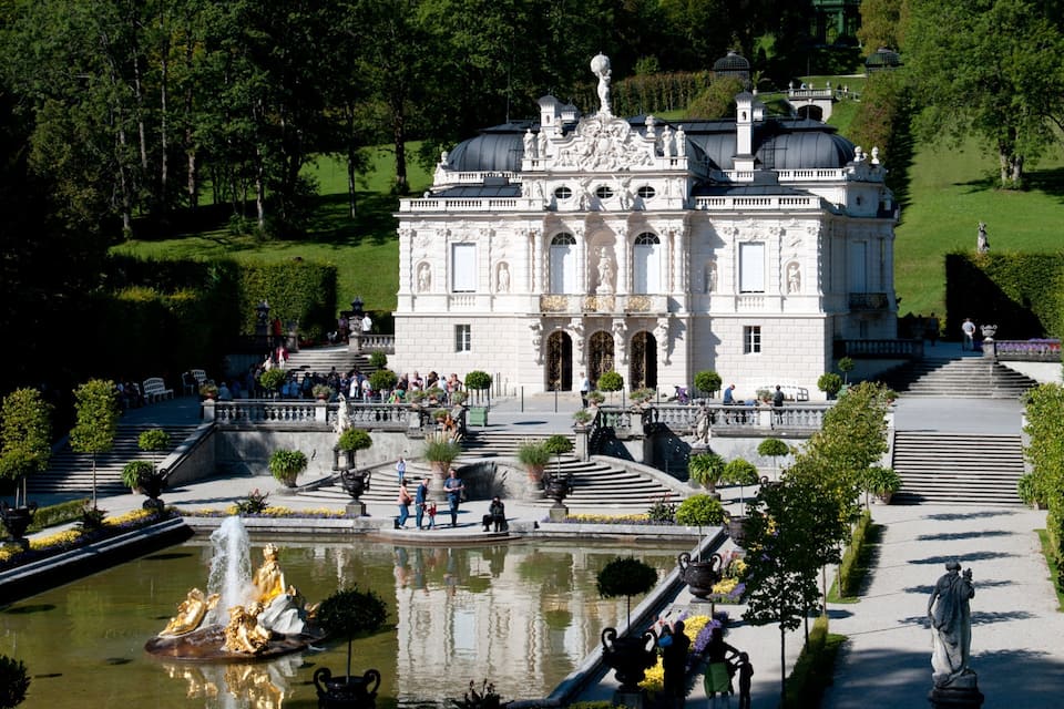 Un palazzo maestoso con architettura elaborata, una fontana centrale e giardini curati.