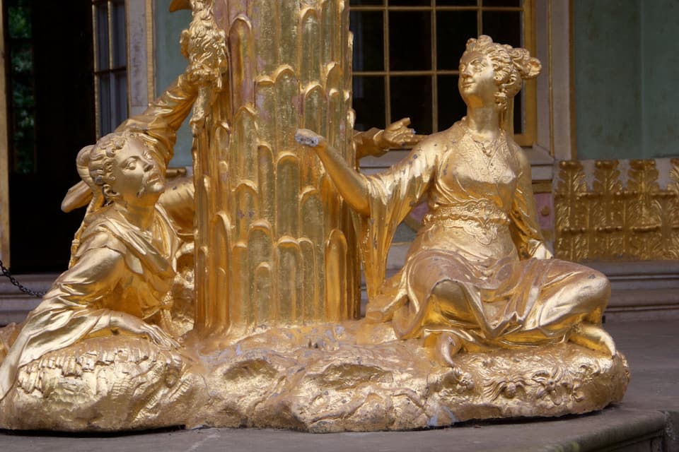 A golden statue of two figures in a fountain.