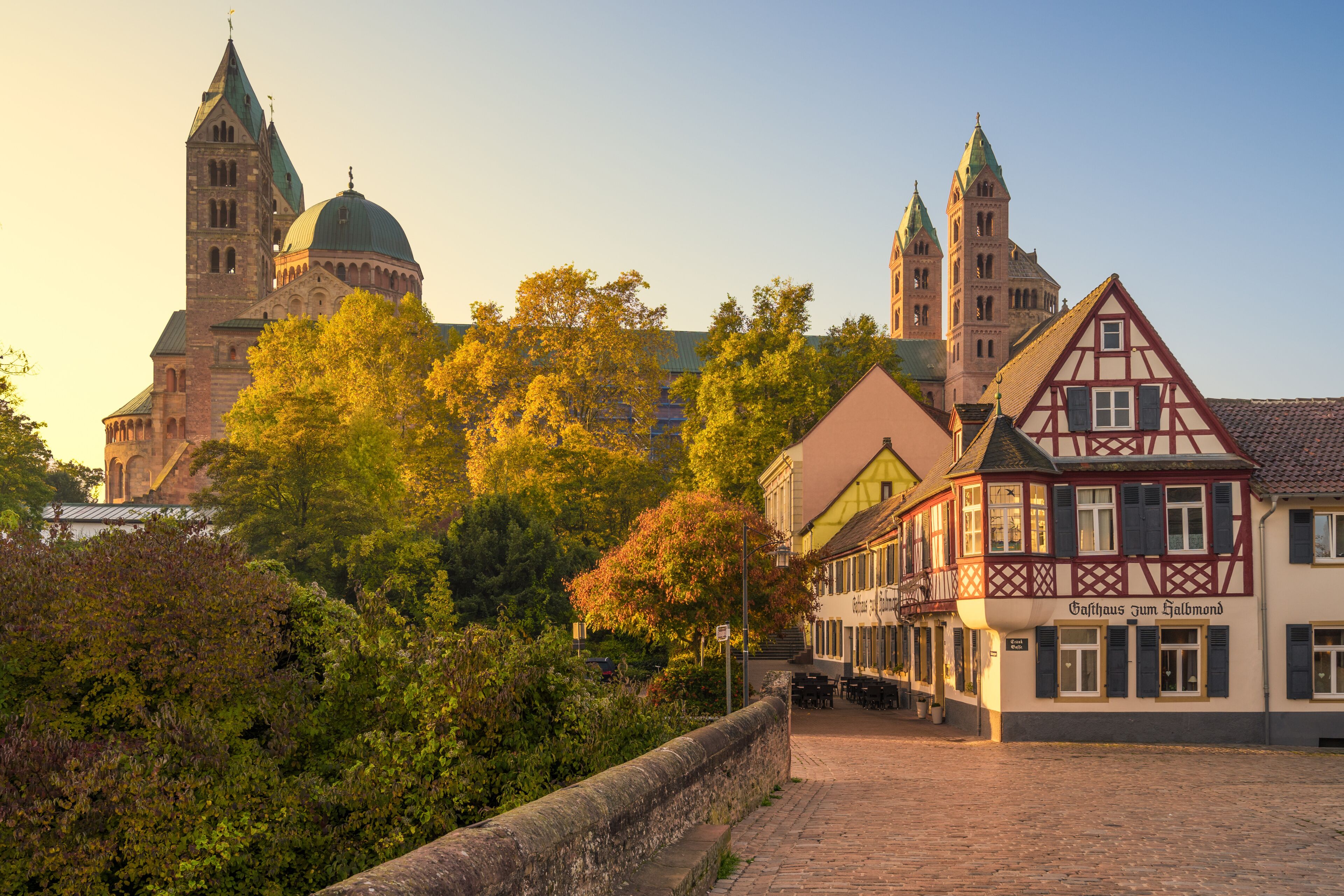 A historic church with twin spires, a traditional half-timbered building, and a cobblestone street.