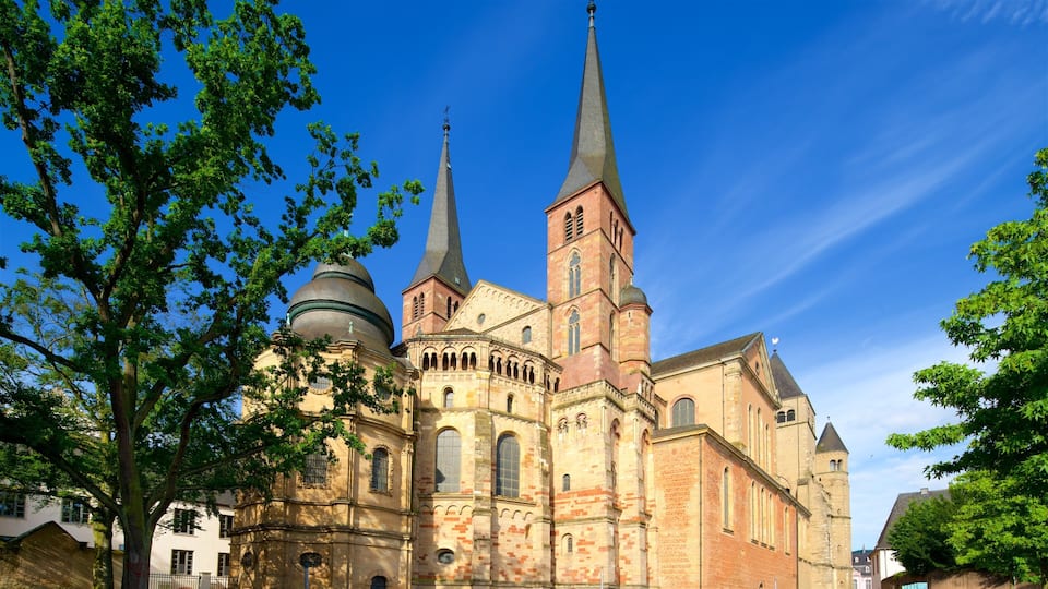 A historic church with two tall spires and a dome, surrounded by trees.