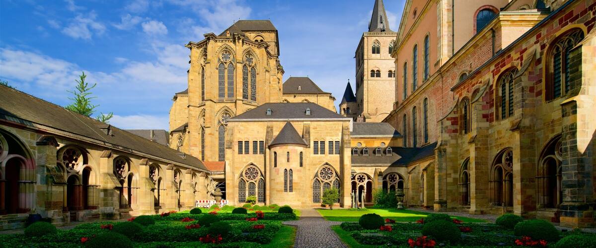 A historic church with a tall tower and arched windows, surrounded by a cobblestone courtyard with well-maintained gardens.