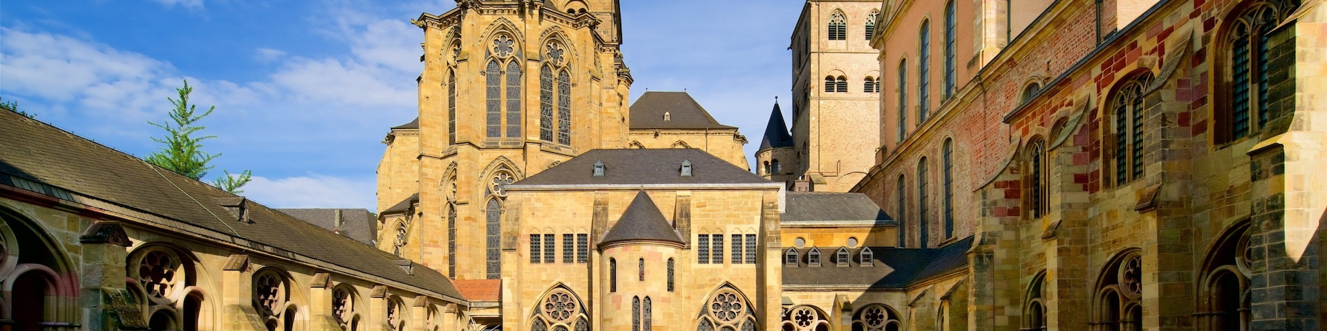 A historic church with a tall tower and arched windows, surrounded by a cobblestone courtyard with well-maintained gardens.