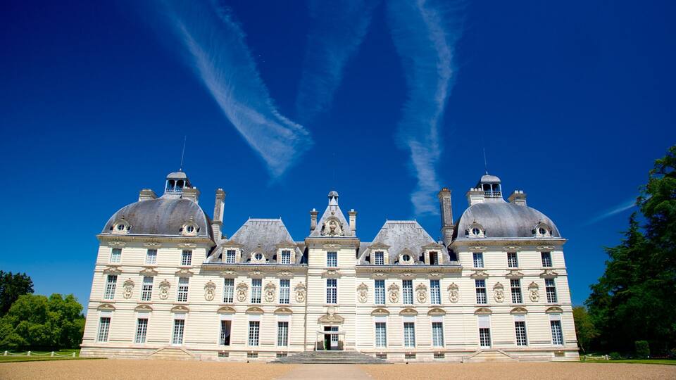 A large, historic building with multiple domes and a symmetrical facade under a clear blue sky.