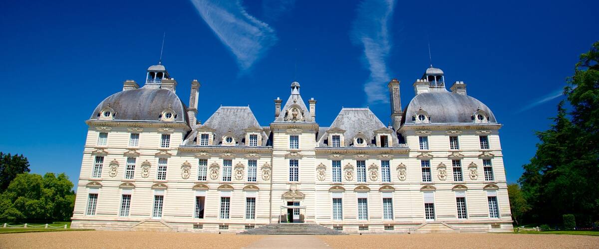 A large, historic building with multiple domes and a symmetrical facade under a clear blue sky.