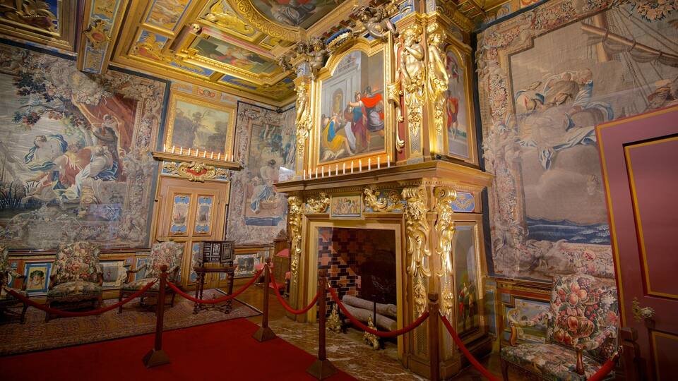 An ornate room with elaborate frescoes, gilded furniture, and a red-roofed fireplace.