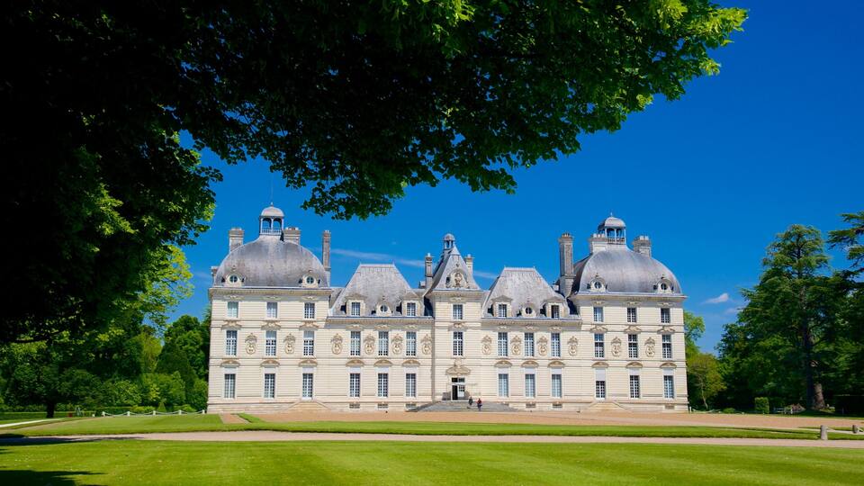 A large, historic building with multiple domes and a symmetrical facade, surrounded by well-maintained lawns and trees.