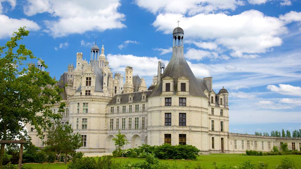 A grand château with multiple towers and a prominent central tower with a cross on top.