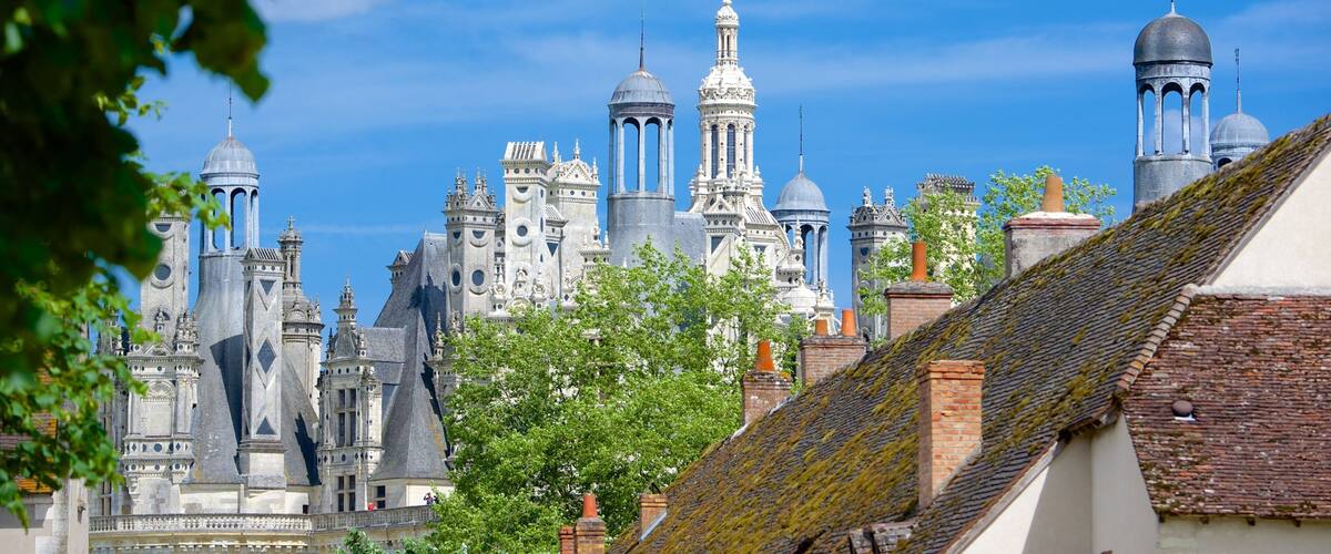 A historic cathedral with multiple spires and domes, surrounded by trees and traditional buildings.