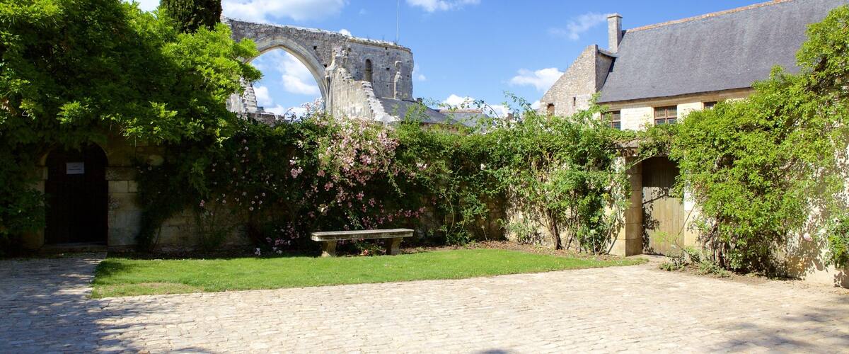 An old stone building with a large archway, surrounded by lush greenery and a cobblestone path.