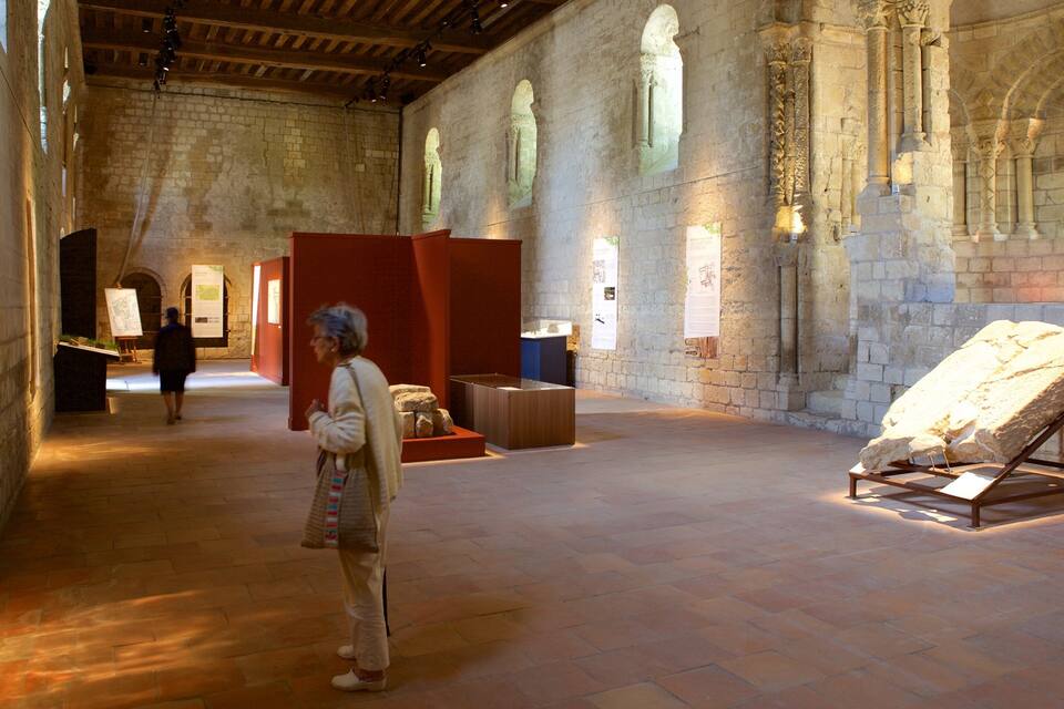 Un edificio histórico con muros de piedra, ventanas de arco y suelo de baldosas.