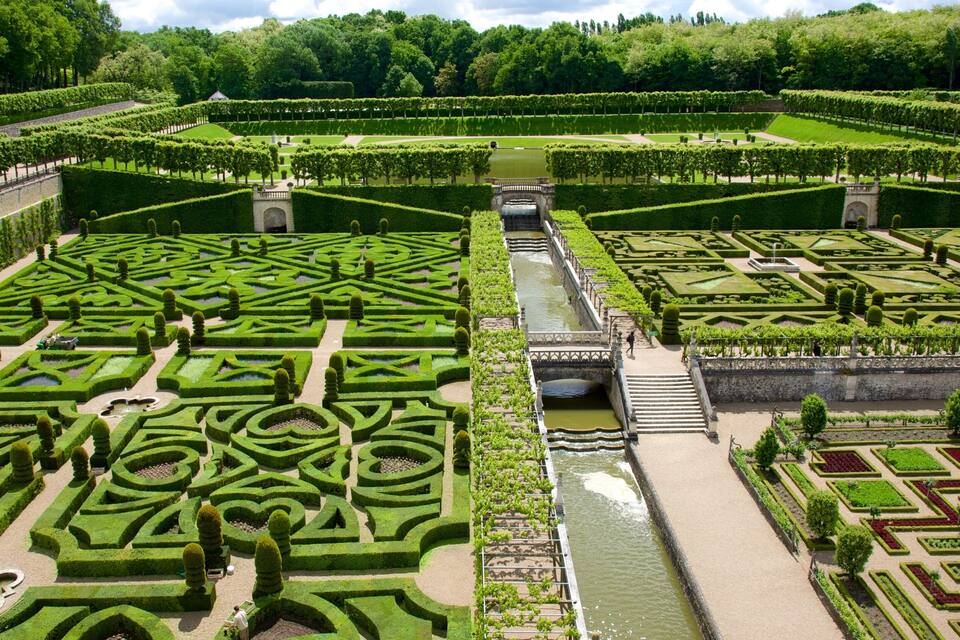 Un jardin aménagé avec le plus grand soin, doté de labyrinthes de haies aux formes géométriques, d’un élément aquatique central et d’un pont en pierre.
