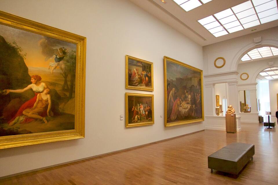 Une galerie d’art spacieuse, avec de grandes peintures classiques accrochées aux murs et un plancher en bois.