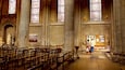 L’intérieur d’une église avec des vitraux, des bancs en bois et des colonnes en pierre.
