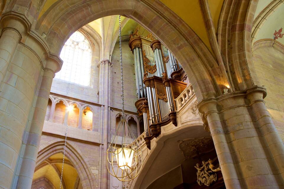 A cathedral interior with Gothic arches, stained glass windows, and ornate pipe organs.