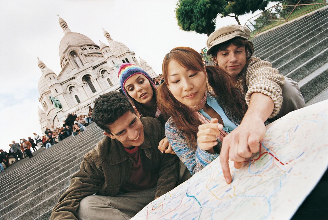 Young Tourist Couples Sitting on the Steps of the Sacre Coeur Basilica, Pointing at a Map, Montmartre, Paris, France