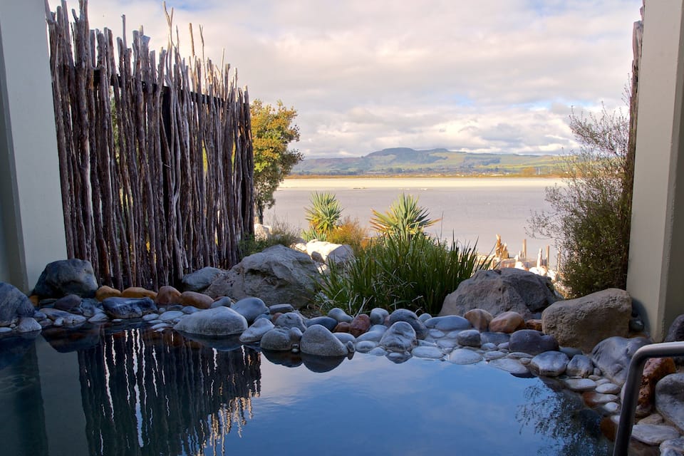 A tranquil indoor pool with a view of a lake and mountains.