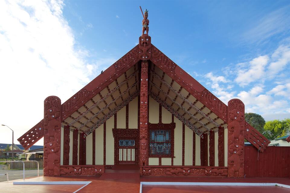 Um edifício tradicional com telhado vermelho, esculturas detalhadas e uma estátua no topo.