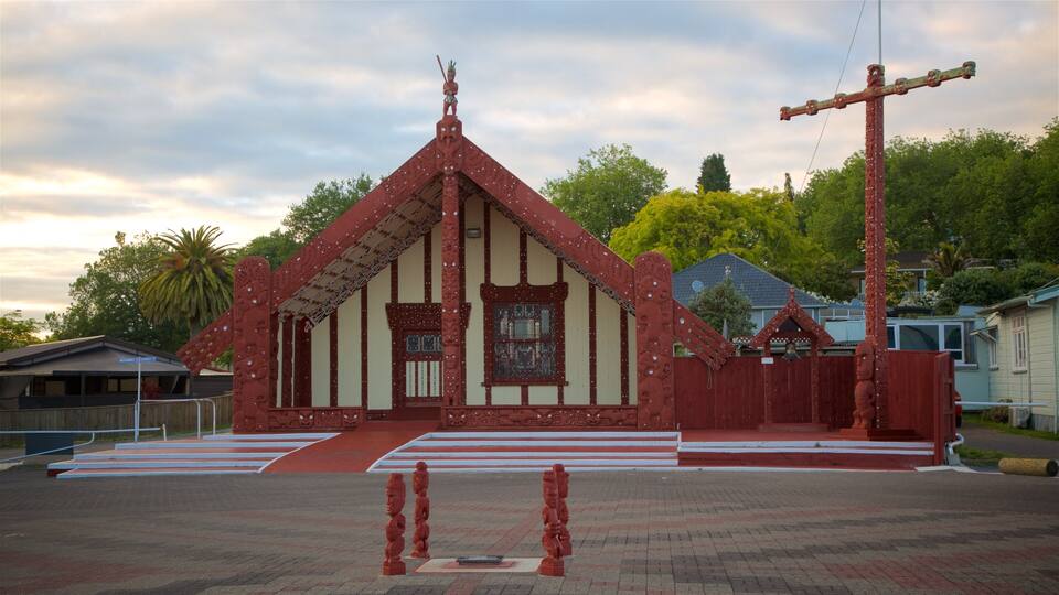 A red church with a cross, surrounded by a paved area with steps leading up to the entrance.