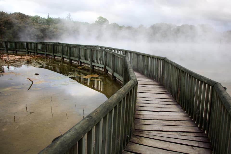 Um calçadão de madeira sobre a água, com vapor subindo da superfície.