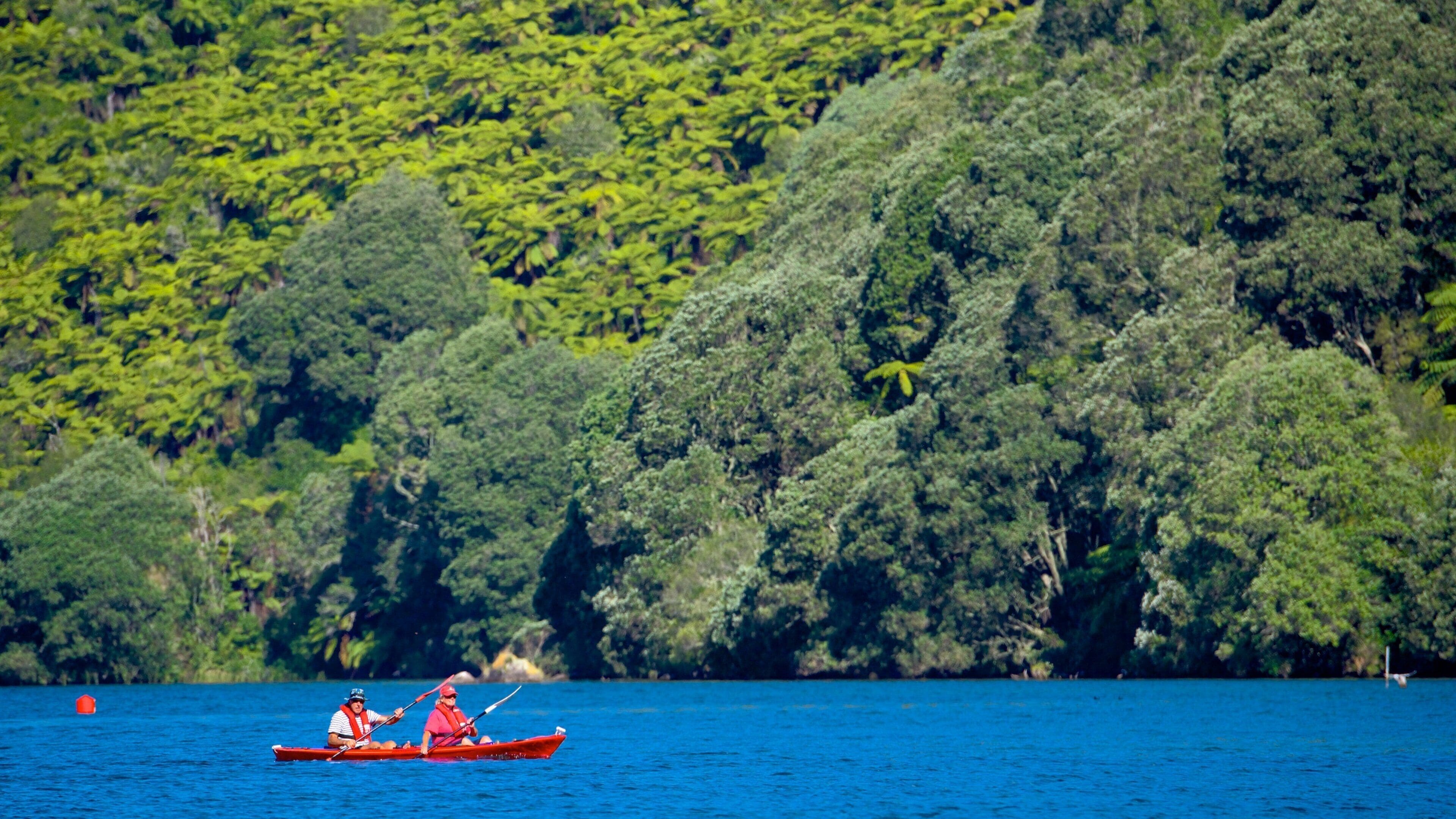 Lake Tarawera featuring a lake or waterhole and kayaking or canoeing as well as a small group of people