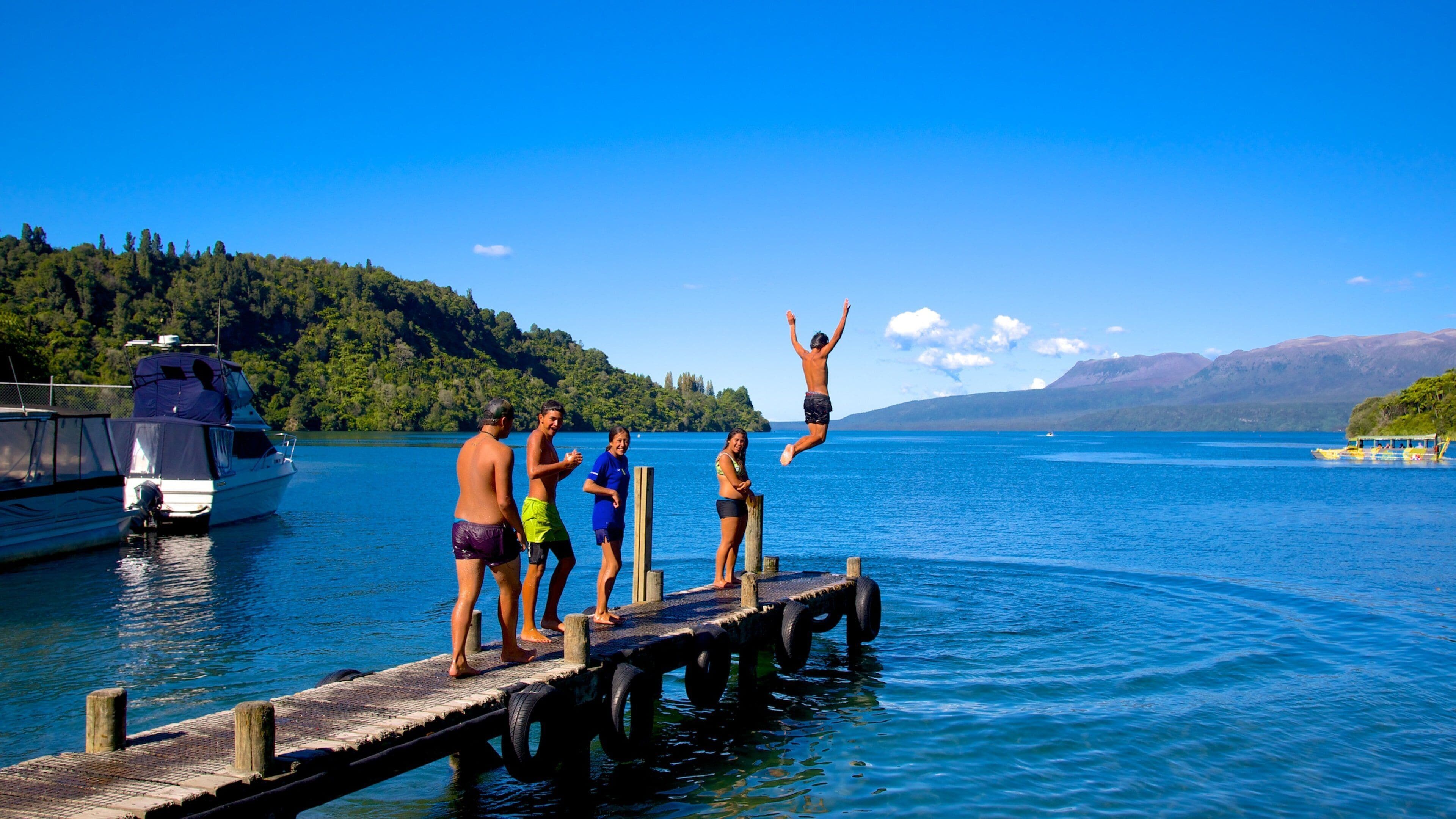Lake Tarawera featuring a lake or waterhole as well as a small group of people