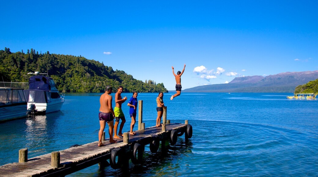Lake Tarawera featuring a lake or waterhole as well as a small group of people