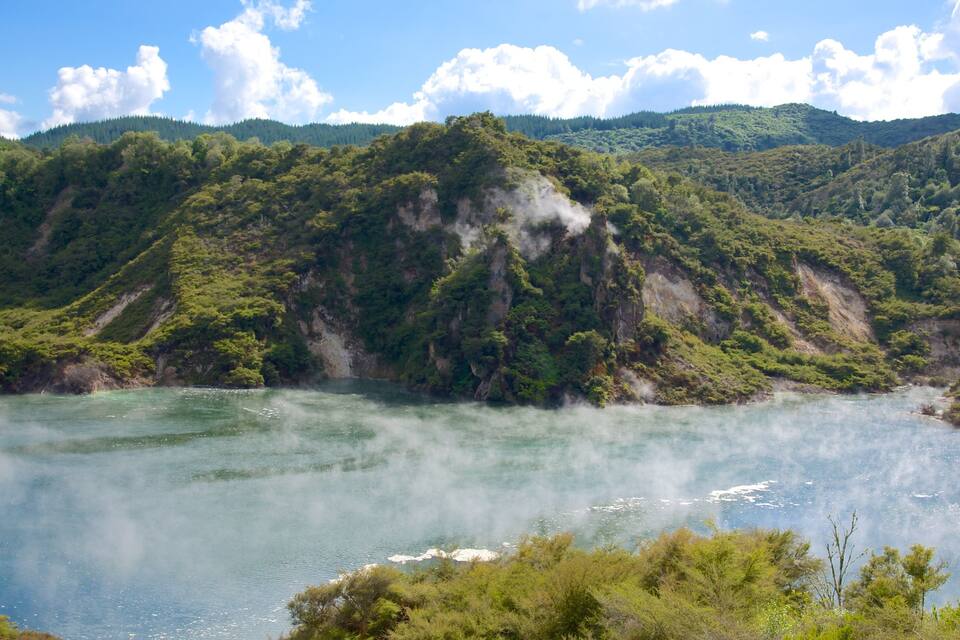 A river surrounded by lush green hills and a clear blue sky.