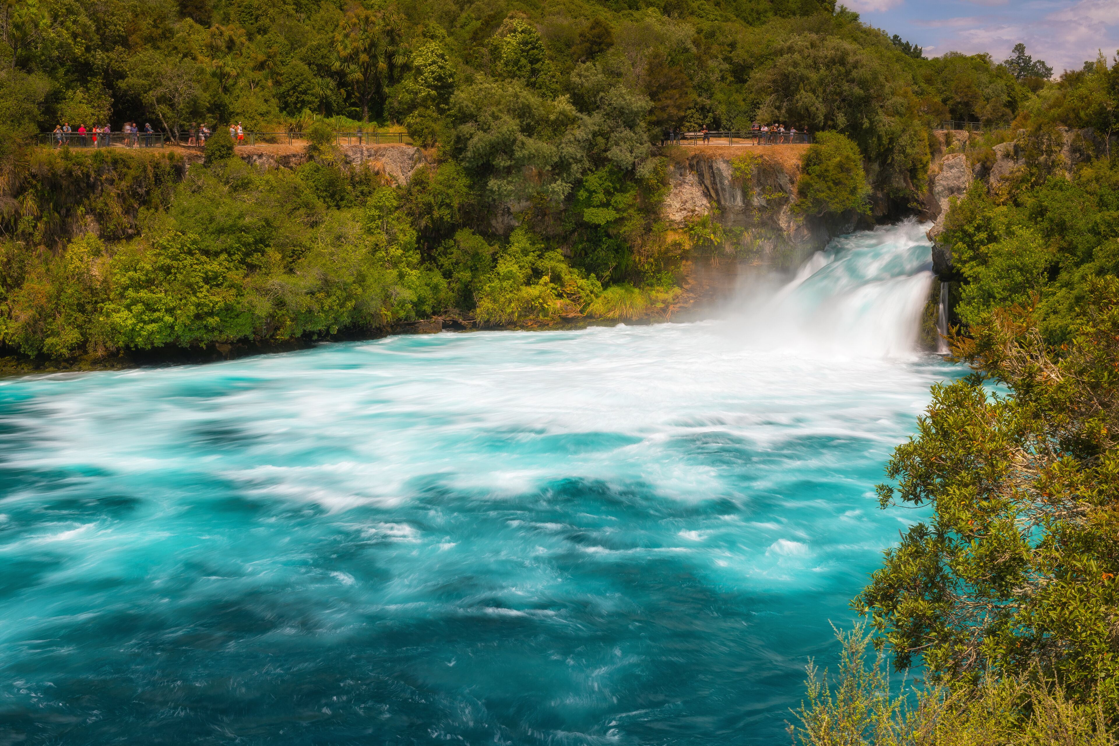 A river with a waterfall surrounded by dense green forest.